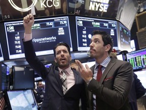 In this Oct. 14, 2014, file photo, Jonathan Scott, left, and Drew Scott, of HGTV's "Property Brothers" cable television show, mimic traders as they visit the post that handles Scripps Networks Interactive, on the floor of the New York Stock Exchange in New York. The company that makes "Property Brothers" and dozens of other TV programs is being sued for millions of dollars in wages, overtime, vacation and public holiday pay claimed on behalf of hundreds of contract production personnel.