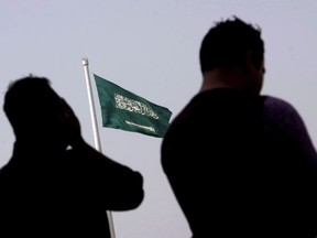 People pray at an open air makeshift mosque in front of a Saudi Flag in Jiddah, Saudi Arabia.