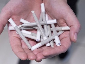 A employee holds pre-rolled joints at Buddha Barn Craft Cannabis in Vancouver, Tuesday, Oct. 2, 2018. While cannabis becomes legal across Canada on Wednesday, Canada's Arctic territories will allow communities to prevent stores from opening to sell the drug.