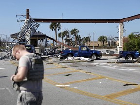 A soldier stands guard at the damaged entrance to Tyndall Air Force Base in the aftermath of hurricane Michael in Panama City, Fla., on October 11, 2018. Thirty Canadian military members and their families are living in a hotel in Florida after a hurricane ripped through the U.S. air force base where they are stationed and damaged their homes. NORAD deputy commander Lt.-Gen. Chris Coates says most of the Canadians were evacuated before Hurricane Michael slammed into Tyndall Air Force Base on Oct. 10, and no injuries were reported.