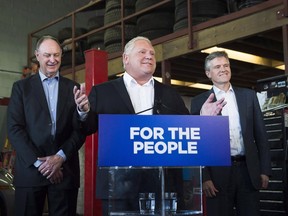 Premier Doug Ford, centre, speaks to the media with Rod Phillips, right, Minister of the Environment, Conservation and Parks, and John Yakabuski, Minister of Transportation regarding the decision to cancel the Ontario Drive Clean program in Toronto, on Friday, September 28, 2018. As of April 1, 2019, drivers will no longer be required to get emissions tests for their passenger vehicles.