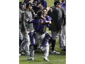 Colorado Rockies catcher Tony Wolters, rear, and left fielder Gerardo Parra, front, celebrate their win against the Chicago Cubs in the National League wild-card playoff baseball game, Wednesday, Oct. 3, 2018, in Chicago. The Rockies won 2-1.