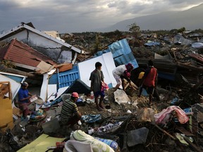 In this Friday, Oct. 5, 2018, photo, a family scavenges for salvageable items from the ruins of their house at Petobo neighborhood which was wiped out by liquefaction caused by a massive earthquake in Palu, Central Sulawesi, Indonesia. Many in the decimated village had no idea they were in an area already identified as a high-risk zone for this apocalyptic phenomenon that causes soft ground to liquefy during temblors. The area around Sulawesi island's Palu Bay had been slammed before and was due for another potential perfect storm, capable of unleashing earthquakes, landslides, tsunami waves, and soil liquefaction.