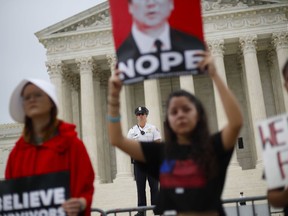 A police officer guards the front steps of the Supreme Court in Washington as activists protest, Tuesday, Oct. 9, 2018. A Supreme Court with a new conservative majority takes the bench as Brett Kavanaugh, narrowly confirmed after a bitter Senate battle, joins his new colleagues to hear his first arguments as a justice.