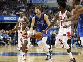 Chicago Bulls guard Kris Dunn (32) and guard Justin Holiday (7) try to get the ball from Dallas Mavericks guard Luka Doncic (77) during the second half of an NBA basketball game in Dallas, Monday, Oct. 22, 2018.