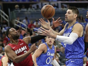 Miami Heat's Dwyane Wade, left, and Orlando Magic's Nikola Vucevic go after a loose ball during the first half of an NBA basketball game, Wednesday, Oct. 17, 2018, in Orlando, Fla.