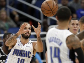 Orlando Magic's Evan Fournier (10) takes a pass from guard D.J. Augustin (14) during the second half of an NBA preseason basketball game against the San Antonio Spurs, Friday, Oct. 12, 2018, in Orlando, Fla.