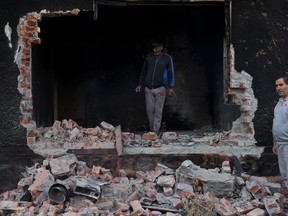 Kashmiri men inspect a damaged house after a gunbattle between suspected militants and Indian security foces in Srinagar, India, Wednesday, Oct. 24, 2018. Indian troops laid a siege around a neighborhood in Srinagar following a tip that militants were hiding there, police said. The searches by troops triggered an exchange of gunfire resulting in the deaths of two militants and injuries to four soldiers and two counterinsurgency policemen.