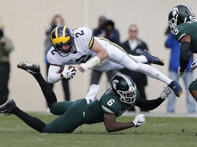 Michigan quarterback Shea Patterson (2) is upended by Michigan State safety David Dowell (6) during the first half of an NCAA college football game, Saturday, Oct. 20, 2018, in East Lansing, Mich.