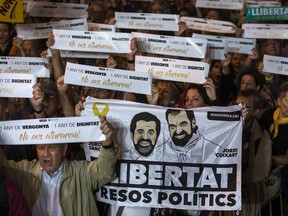 Demonstrators hold up a poster of Jordi Sanchez and Jordi Cuixart, during a protest in support of Catalonian politicians and leaders of two civil society groups who have been jailed on charges of sedition in Barcelona, Spain, Tuesday, Oct. 16. 2018. Politicians, rights groups and citizens across Catalonia are calling for the release of jailed separatists as they mark one year since two prominent pro-independence activists, Jordi Sanchez and Jordi Cuixart, leaders of two civil society groups _ ANC and Omnium Cultural, respectively _ were put in pre-trial detention. Banners reads in Catalan "one year of shame, on year of dignity"
