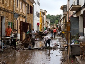 Residents clear mud from a flooded dstreet in Sant Llorenc, 60 kilometers (40 miles) east of Mallorca's capital, Palma, Spain, on Wednesday, Oct. 10, 2018. Torrential rainstorms that caused flash flooding of water and mud on the Spanish island of Mallorca killed at least nine people, authorities said on Wednesday.
