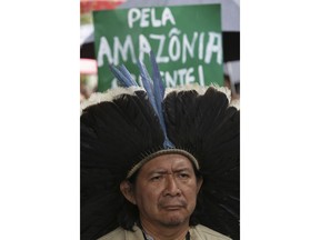 Indigenous leader Kreta Kaingang stands in front of  a sign that reads in Portuguese "For the Amazon. Urgent!"  during a protest against right-wing presidential candidate Jair Bolsonaro, in front of the Ministry of Environment in Brasilia, Brazil, Oct. 19, 2018. Environmental movements reacted after Bolsonaro announced in his government program that he will merge the Ministry of the Environment with the Ministry of Agriculture and will pull Brazil from the Paris Agreement.