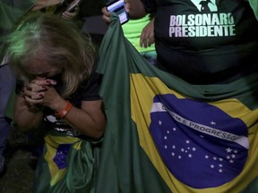 A supporter of presidential frontrunner Jair Bolsonaro of the Social Liberal Party, pray as they wait for the first results of the vote counting of the presidential elections, in front of the headquarters of the national congress, in Brasilia, Brazil, Sunday, Oct. 7, 2018.