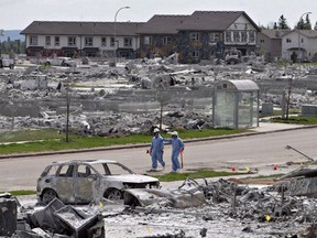 Workers put out markers around a devastated area of Timberlea in Fort McMurray Alta, on Thursday, June 2, 2016. Newly published research suggests the fire cast a lasting shadow over the lives of many residents who are still experiencing elevated rates of depression and related mental-health problems.