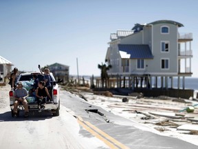 People drive along a damaged road in the aftermath of hurricane Michael in Mexico Beach, Fla., Friday, Oct. 12, 2018.