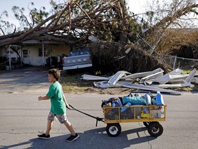 Anthony Weldon, 11, pulls a cart with his family's belongings as they relocate from their uninhabitable damaged home to stay at their landlord's place in the aftermath of Hurricane Michael in Springfield, Fla., Monday, Oct. 15, 2018.