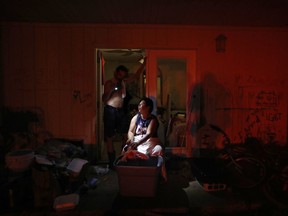 Tasha Hughes, bathes her daughter, Madison, 4, as Jeffrey Dumich holds a flashlight outside their room at the damaged American Quality Lodge where they continue to live without power in the aftermath of Hurricane Michael, in Panama City, Fla., Tuesday, Oct. 16, 2018. Simply getting through the day is a struggle at the low-rent motel where dozens of people are living in squalor amid destruction left by the hurricane.