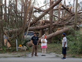 Joyce Fox, center stands in front of her heavily damaged home in the aftermath of Hurricane Michael in Panama City, Fla., Thursday, Oct. 11, 2018.