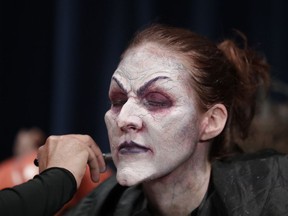 In this Wednesday, Sept. 12, 2018 photo, Laura Law sits as make up artist Eric Garcia works his craft turning her into a witch for Halloween Horror nights at Universal Studios in Orlando, Fla.