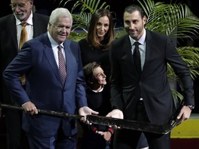 Florida Panthers goaltender Roberto Luongo, right, is presented with a gold-covered hockey stick by Florida Panthers general manager Dale Tallon, left, before an NHL hockey game against the Vancouver Canucks, Saturday, Oct. 13, 2018, in Sunrise, Fla. Luongo was honored for reaching his 1,000th NHL game.