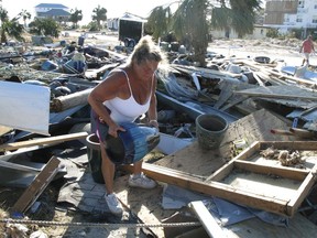 In this Oct. 14, 2018 photo Dena Frost salvages an unbroken clay pot from the wreckage of her pottery business in Mexico Beach, Fla. For decades, the town has persisted as a stubbornly middlebrow enclave on what residents proudly refer to as Florida's "Forgotten Coast." Businesses are locally owned. While some locals owned posh homes that overlooked the beach on stilts, many lived in mobile homes.