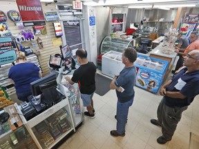 Customers line up to purchase lottery tickets, Monday, Oct. 22, 2018, at La Preferida Superdiscount store in Hialeah, Fla. Lottery players will have a chance at winning an estimated $1.6 billion jackpot in Tuesday night's Mega Millions drawing and an estimated $620 million in Wednesday night's Powerball jackpot.