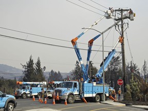 FILE - In this Oct. 11, 2017 file photo, a Pacific Gas & Electric crew works at restoring power along the Old Redwood Highway in Santa Rosa, Calif. Northern California's biggest utility has taken the unprecedented step of cutting electricity for tens of thousands of customers in an attempt to prevent wildfires amid rising winds and official warnings on Monday, Oct. 15, 2018, of extreme fire danger. Pacific Gas & Electric began turning off the lights in California's wine country north of San Francisco and Sierra Nevada foothills east of Sacramento Sunday night. The utility said at least 87,000 customers had their power turned off and that more could be put in the dark depending on the weather.