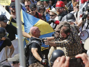 FILE - In this Aug. 12, 2017 file photo, white nationalist demonstrators clash with counter demonstrators at the entrance to Lee Park in Charlottesville, Va. The leader of a Southern California white supremacist group and three other members have been arrested weeks after indictments of other group members for allegedly inciting the riot last year in Charlottesville, Virginia. U.S. Attorney's Office spokesman Thom Mrozek says Rise Above Movement leader Robert Rundo was arrested Sunday at Los Angeles International Airport and is expected in Los Angeles federal court Wednesday, Oct. 24, 2018.