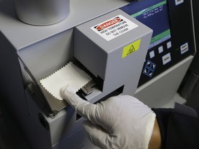 FILE - In this May 20, 2015 file photo, Correctional Officer M. Jones, puts a test sample on an airport-style ion spectrometer that tests for illegal narcotics at Vacaville State Prison in Vacaville, Calif. The federal receiver who controls medical care in California state prisons is seeking up to a quarter-billion dollars annually to provide medication designed to stem a record increase in fatal drug overdoses among inmates.