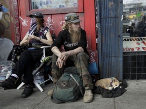 In this Oct. 1, 2018 photo, Stormy Nichole Day, left, sits on a sidewalk on Haight Street with Nord (last name not given) and his dog Hobo while interviewed about being homeless in San Francisco. A measure on San Francisco's Nov. 6 ballot would levy an extra tax on hundreds of the city's wealthiest companies to raise $300 million for homelessness and mental health services. It's the latest battle between big business and social services advocates who say that companies such as Amazon, Google and Salesforce can afford to help solve severe inequities caused by business success.