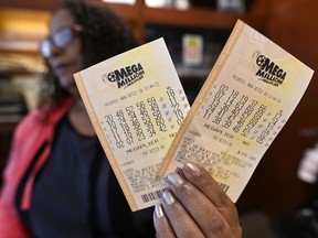 A shop employee in Atlanta holds Mega Millions lottery tickets, Monday, Oct. 22, 2018. No one won the $1 billion jackpot in Saturday night's drawing, which means the top prize for Tuesday night's Mega Millions drawing would be the largest lottery jackpot in U.S. history.