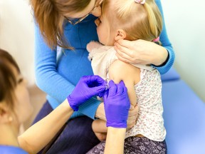 Doctors hand in gloves holding syringe and making  kids vaccination  against flue.