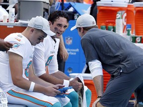Miami Dolphins quarterback Brock Osweiler (8), talks to injured quarterback Ryan Tannehill, during the second half of an NFL football game against the Chicago Bears, Sunday, Oct. 14, 2018, in Miami Gardens, Fla.