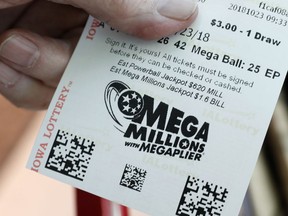 A customer shows his Mega Millions lottery ticket at a local grocery store, Tuesday, Oct. 23, 2018, in Des Moines, Iowa. Lottery players will have a chance at winning an estimated $1.6 billion jackpot in Tuesday night's Mega Millions drawing.