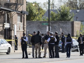 In this Monday, Oct. 22, 2018 photo, Chicago Police investigate following a shooting after a funeral service in Chicago. Police scrambled Tuesday to ward off retaliatory attacks by street gangs after a Chicago rapper known for taunting rivals on social media was shot in the head in a shootout during a funeral for another area rapper fatally shot earlier this month.