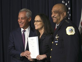 FILE - In this Sept. 13, 2918, file photo, Illinois Attorney General Lisa Madigan, center, Chicago police Superintendent Eddie Johnson, right, and Mayor Rahm Emanuel hold up a copy of the proposed consent decree during a news conference in Chicago. A federal judge who will decide whether to approve a lengthy court-oversight plan to reform the Chicago Police Department started a highly anticipated two-day hearing Wednesday, Oct. 24, 2018, by saying he would allow dozens of people to voice their opinions on the proposal. The plan hammered out by city officials and the Illinois Attorney General's Office has widespread support in minority neighborhoods that have long been suspicious of police and complained about police misconduct.