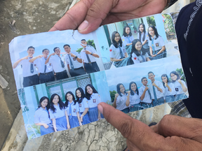 Muis Pangalo, 45, holds up a photo pulled from the debris, showing his daughter among friends at a Bible study camp. She is believed to be buried under the rubble in Jono Oge.