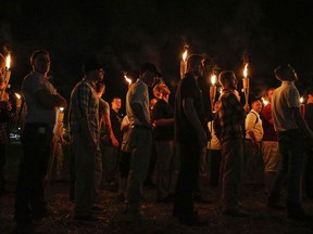 FILE - In this Aug. 11, 2017, file photo, multiple white nationalist groups march with torches through the University of Virginia campus in Charlottesville, Va. Multiple arrests have been made in connection with a white nationalist torch-lit march and rally in Charlottesville, Virginia, last year, federal authorities said Tuesday, Oct. 2, 2018.