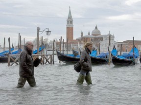 People walk on a flooded quay of Venice.
