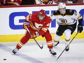 Boston Bruins' Brandon Carlo, right, and Calgary Flames' Sean Monahan chase the puck during NHL hockey action in Calgary, Wednesday, Oct. 17, 2018.THE CANADIAN PRESS/Jeff McIntosh