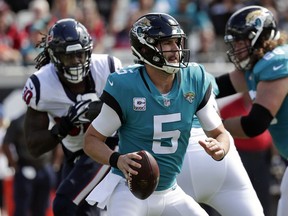 Blake Bortles (5) looks for a receiver as he is pressured by Houston Texans linebacker Jadeveon Clowney, back left, during the first half of an NFL football game, Sunday, Oct. 21, 2018, in Jacksonville, Fla.