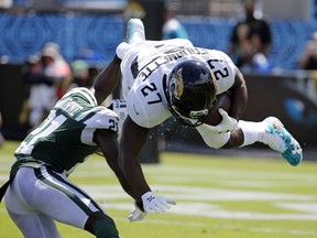 New York Jets cornerback Morris Claiborne, left, upends Jacksonville Jaguars running back Leonard Fournette (27) during the first half of an NFL football game, Sunday, Sept. 30, 2018, in Jacksonville, Fla.