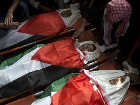 Relatives mourn over the bodies of three teens, wrapped in Palestinian flags, who were killed in an Israeli airstrike on Sunday, during their funeral in the town of Deir el-Balah, central Gaza Strip, Monday, Oct. 29, 2018. Hundreds of Palestinians laid them to rest, with their families insisting they had no militant ties and calling on Gaza's militant groups to retaliate.