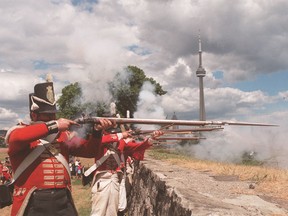 Members of the 8th King’s Regiment fire muskets from the walls of Fort York to mark Simcoe Day, honouring Lt.-Gov. John Graves Simcoe. Toronto's iconic CN Tower is seen in the background.