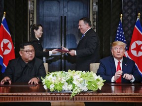 This handout photo taken on June 12, 2018 and released by The Straits Times shows US President Donald Trump (R) and North Korea's leader Kim Jong Un (L) looking on as documents are exchanged between US Secretary of State Mike Pompeo (2nd R) and the North Korean leader's sister Kim Yo Jong (2nd L) at a signing ceremony during their historic US-North Korea summit, at the Capella Hotel on Sentosa island in Singapore.