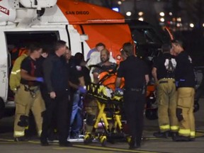 This Oct. 20, 2018 still photo taken from video provided by the United States Coast Guard shows a Coast Guard helicopter crew transferring one of two patients to emergency medical services personnel in San Diego, Calif. Coast Guard officials say three people are missing and 15 people were rescued Saturday, Oct. 20, 2018 after their fishing boat caught fire south of San Diego.