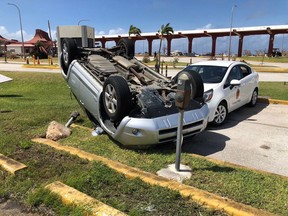 FILE - In this Friday, Oct. 26, 2018, file photo, an overturned car is shown at the airport after Super Typhoon Yutu hit the U.S. Commonwealth of the Northern Mariana Islands in Garapan, Saipan. Elections are being postponed in a Pacific U.S. territory going without electricity after a super typhoon destroyed homes, toppled trees, utility poles and left a woman dead.