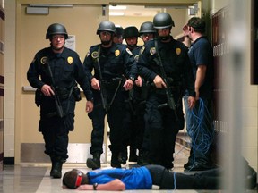 In this May 29, 2008 photo, Baton Rouge Police Department SWAT team members walk down a McKinley Middle Magnet School hallway past a fire academy member playing the role of a victim during a simulated hostage situation in Baton Rouge, La. High-tech hardware installed by NetTalon Security Systems reduced "casualties" during the exercise, according to then-principal Herman Brister. But in hindsight, he said he would have rather hired an armed resource officer.