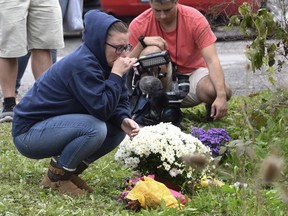 People place flowers, Sunday, Oct. 7, 2018, at the scene where 20 people died as the result of a limousine crashing into a parked and unoccupied SUV at an intersection a day earlier, in Schoharie, N.Y.