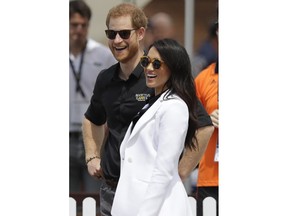 Britain's Prince Harry and Meghan, Duchess of Sussex smile as they meet competitors at the Invictus Games driving challenge on Cockatoo Island in Sydney, Australia, Saturday, Oct. 20, 2018. Prince Harry and his wife Meghan are on day five of their 16-day tour of Australia and the South Pacific.